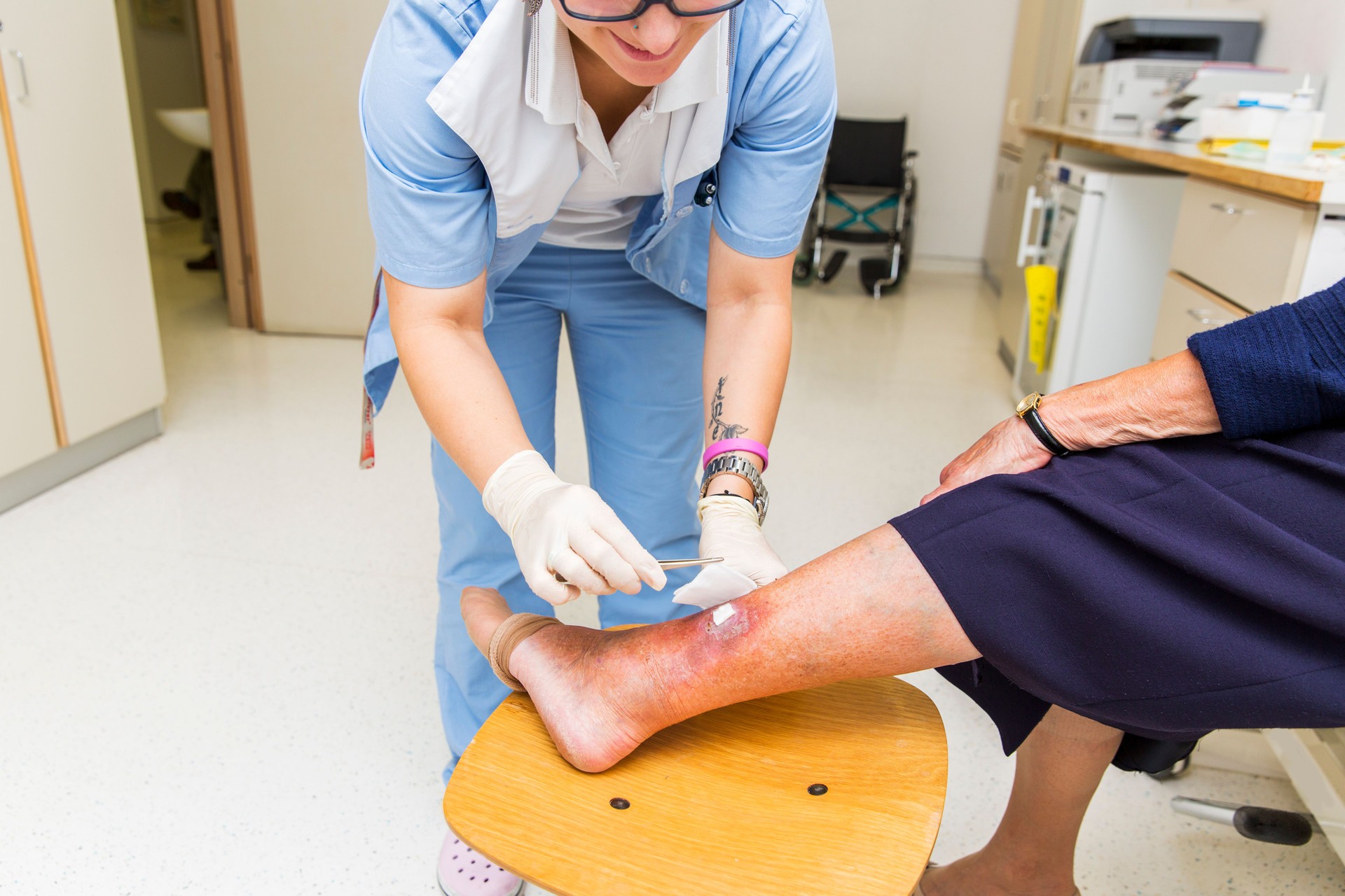 Cute Nurse with tatoo on her forearm is changing bandage